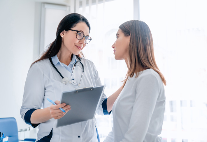 Doctor talking to patient while holding a clipboard during medical consultation